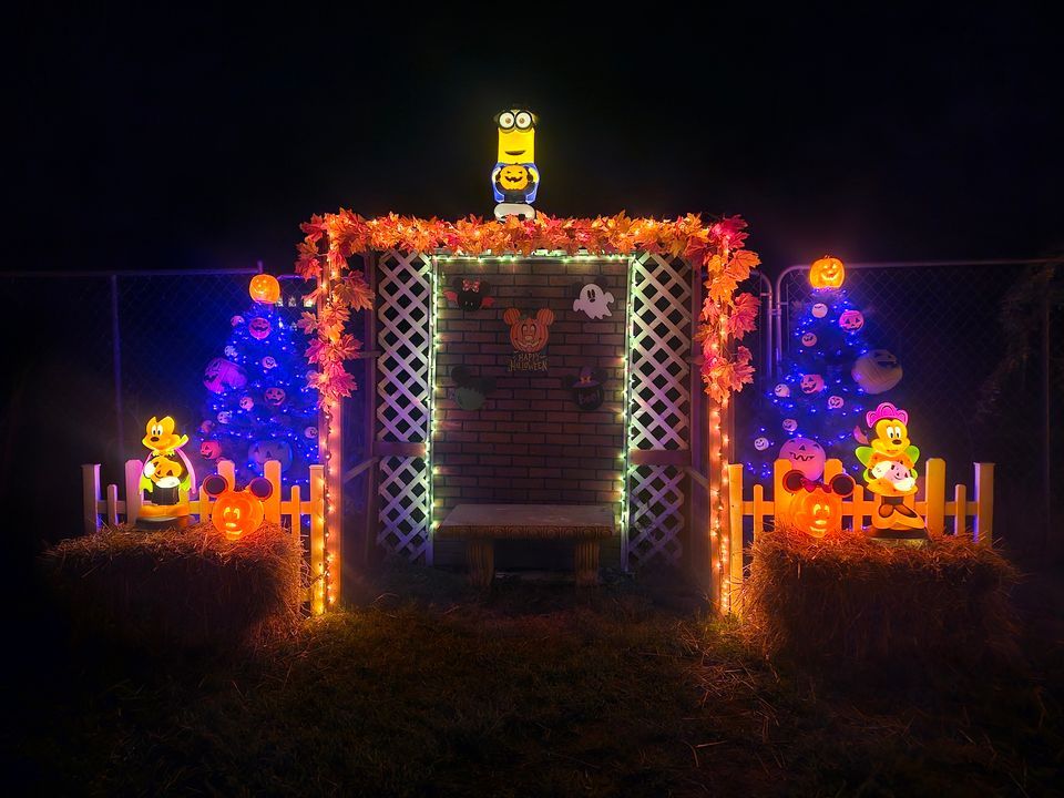 Disney and Minion illuminated family photo bench flanked by hay bales and glowing pumpkins
